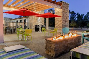 An outdoor patio with a fire pit, red umbrellas, and outdoor seating. - Home2 Suites By Hilton Alcoa Knoxville Airport (Alcoa)