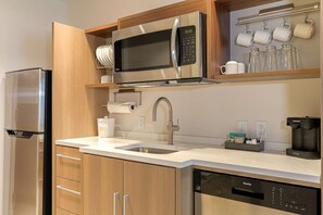 A modern kitchen with a stainless steel refrigerator, a built-in microwave, a double sink, and a coffee maker. - Home2 Suites By Hilton Alcoa Knoxville Airport (Alcoa)