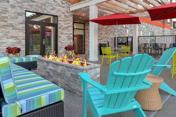 An outdoor seating area with a stone fire pit, colorful striped cushions, and bright turquoise Adirondack chairs.