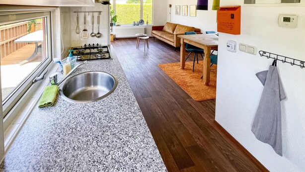 A modern kitchen with a large sink, a dining area with a table and chairs, and a sofa. - Stunning (sta)caravan in Tzummarum (Tzummarum)