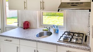 A kitchen with a granite countertop, stainless steel sink, and a gas stove. - Stunning (sta)caravan in Tzummarum (Tzummarum)