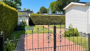 A gated pathway leading to a house with a brick driveway and a neatly trimmed hedge. - Stunning (sta)caravan in Tzummarum (Tzummarum)