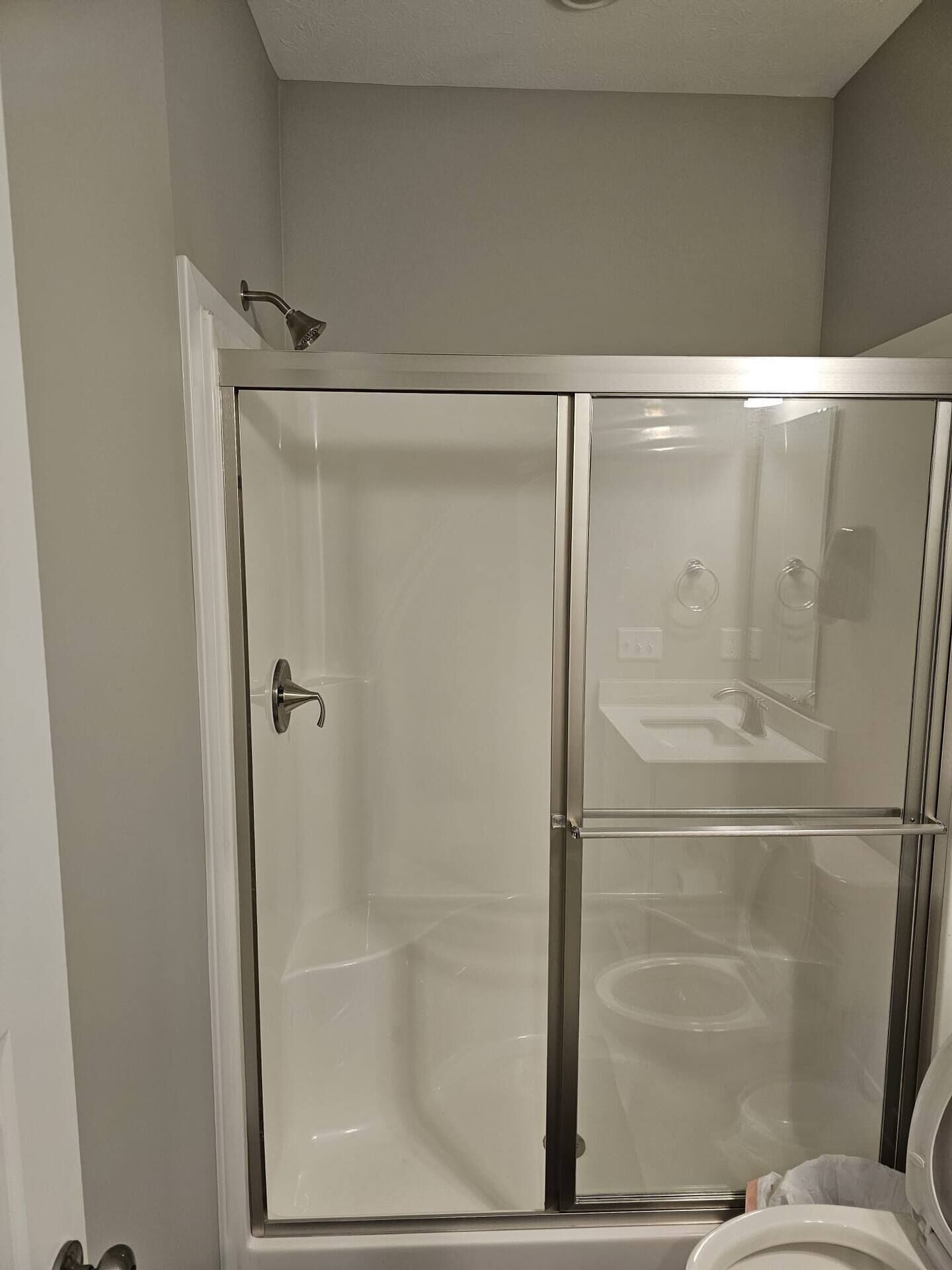 A glass-enclosed shower stall with a white door and a showerhead.