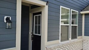 A house with a dark gray exterior, a white door, and a small window with a metal grill.