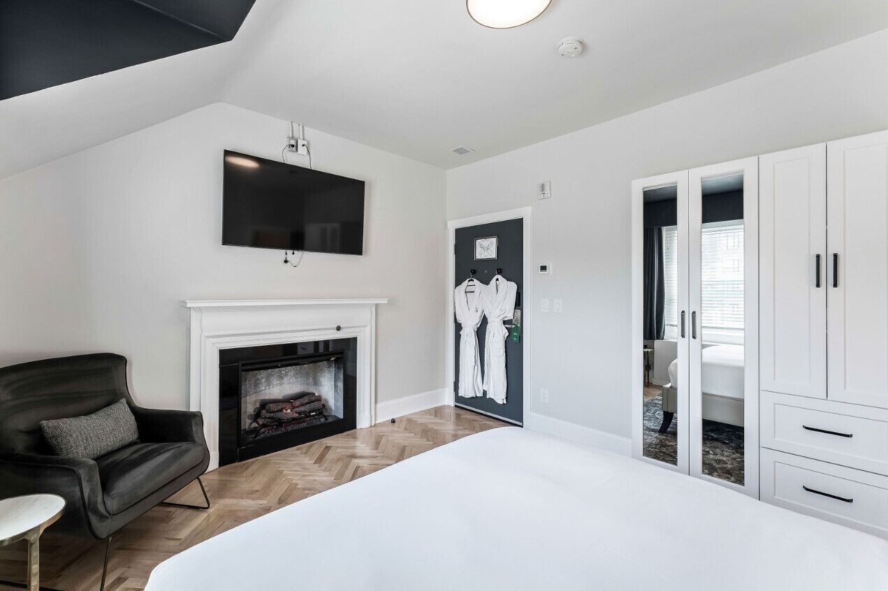 Un dormitorio moderno con chimenea, televisor montado en la pared y vestidor.