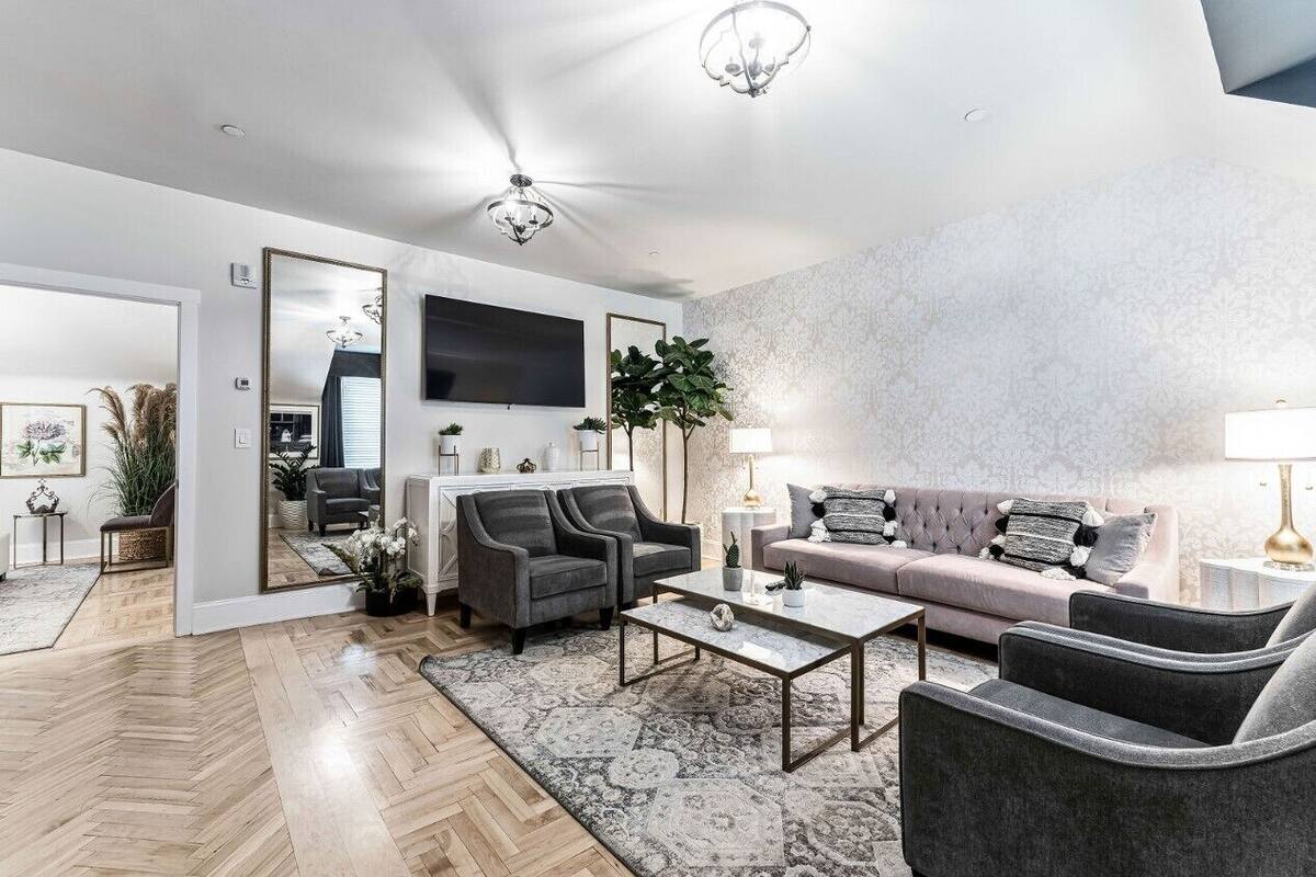 A modern living room with a sofa, armchairs, a coffee table, and a TV mounted on the wall.