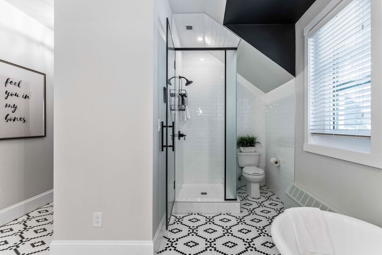 Un baño moderno con ducha, inodoro y suelo estampado.