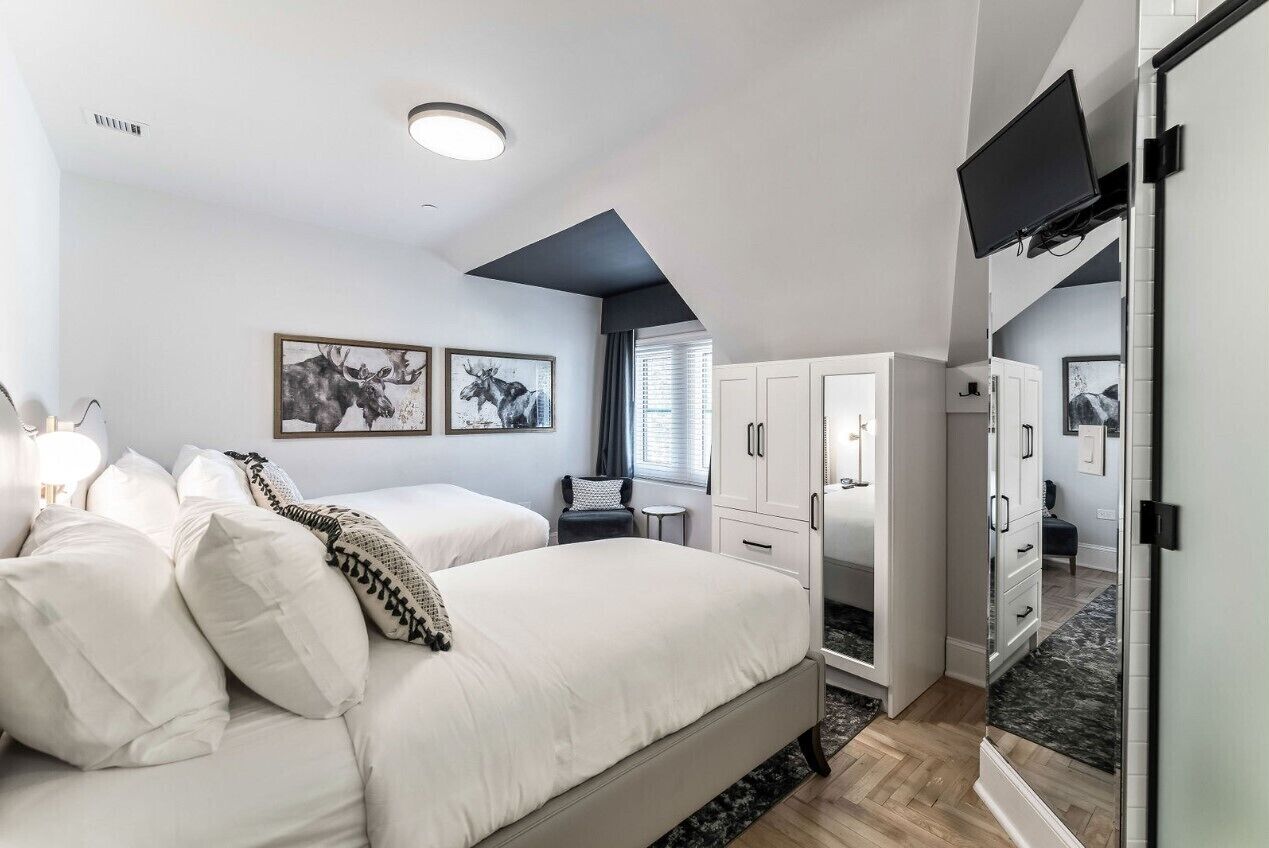 Un dormitorio moderno con dos camas, un escritorio y una televisión.