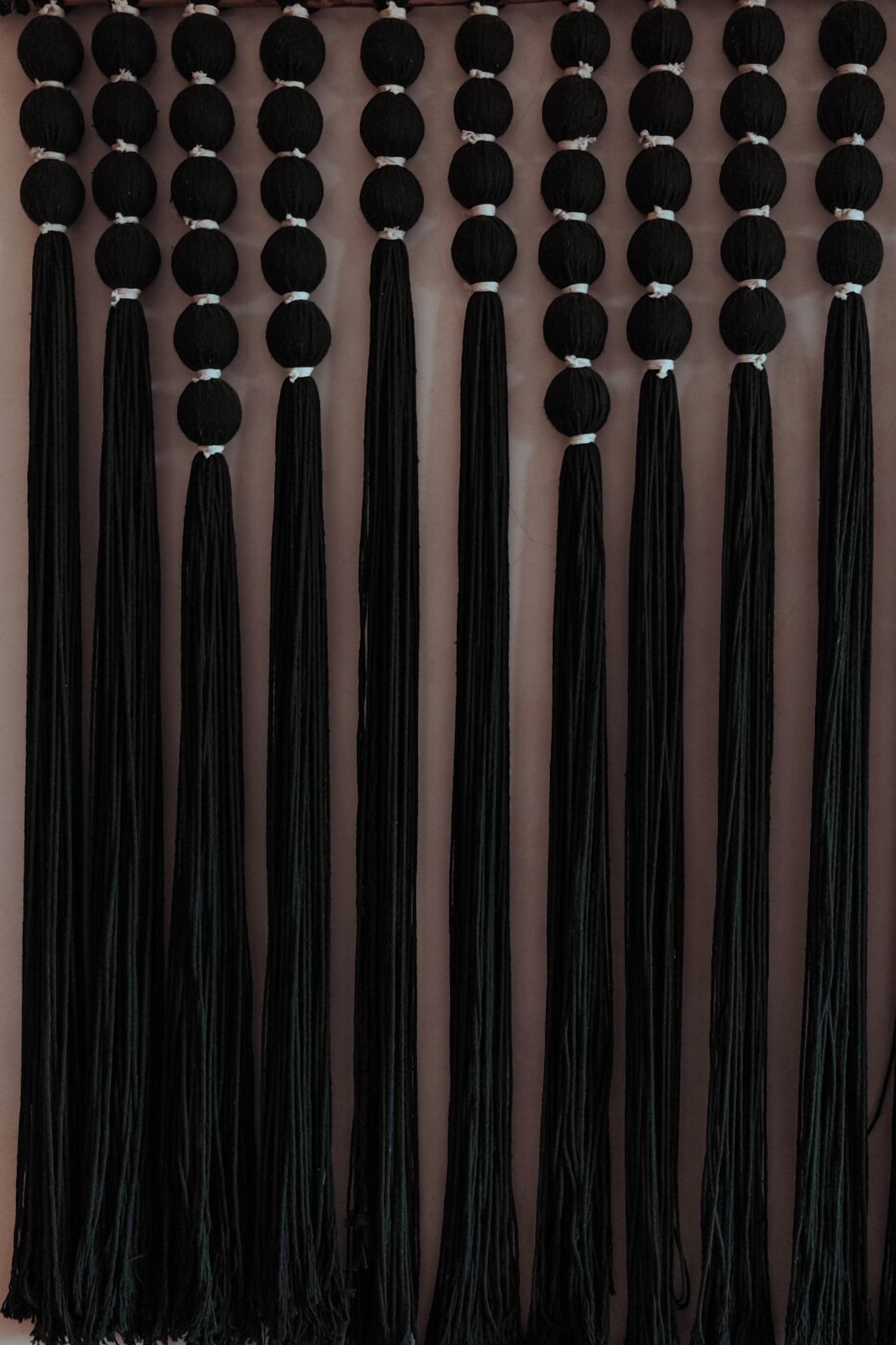 Una pared con múltiples flecos negros colgados en filas.