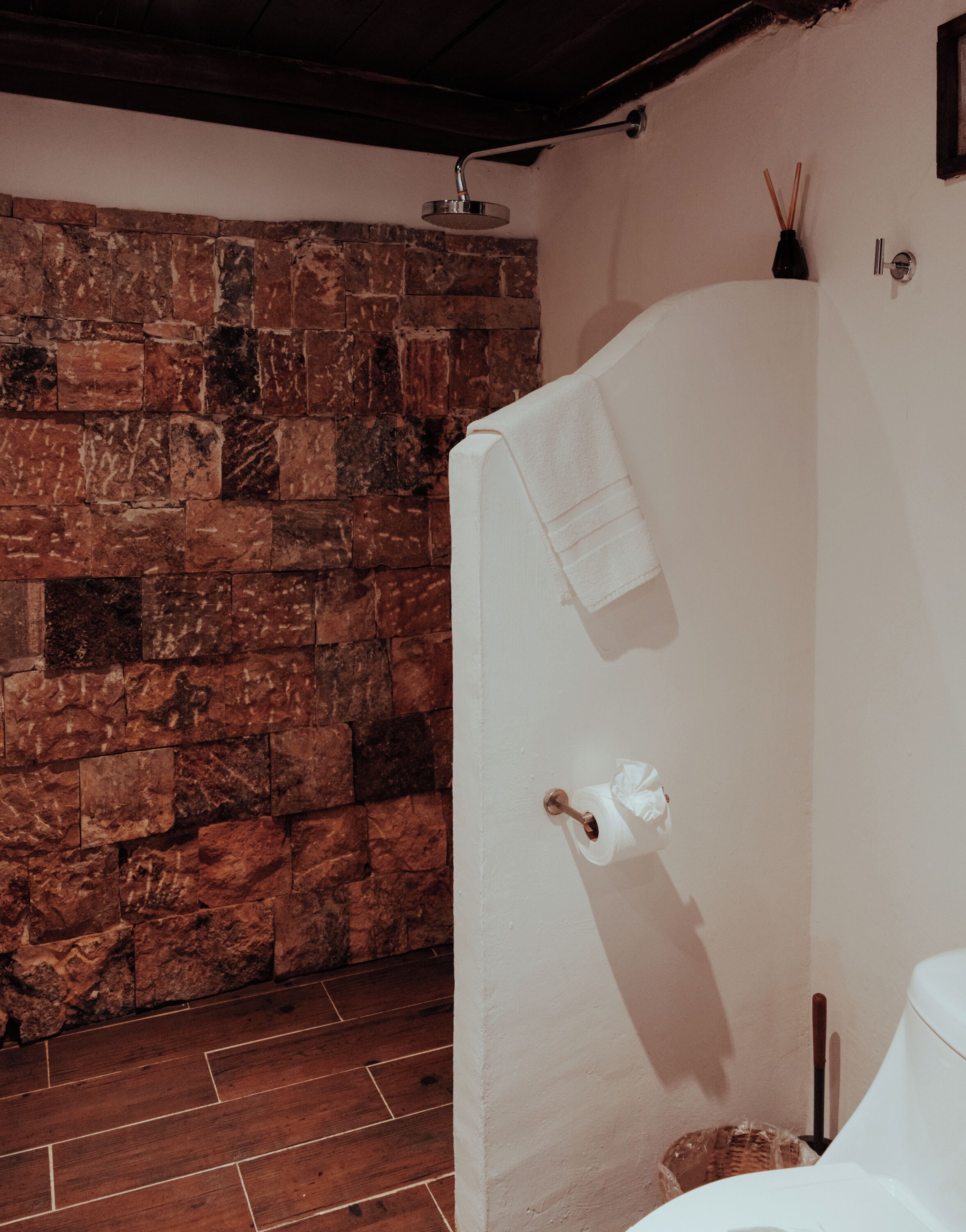 A bathroom with a stone wall, a shower enclosure, and a toilet.