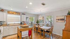 A modern kitchen with white cabinets, a wooden island, and a dining area with wooden chairs and a table. - Open Water~Sunsets~Swimming~Standing Work Station with High Speed Internet~Lake (Mabank)