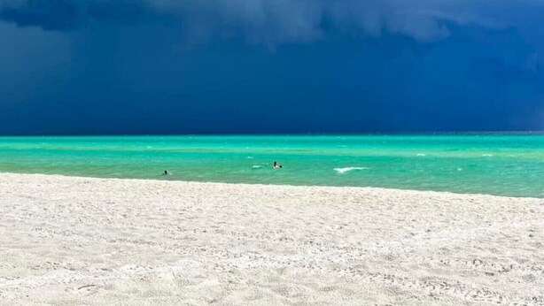 Una playa con aguas turquesas cristalinas y una orilla arenosa.