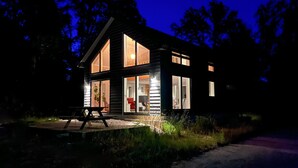 A modern two-story cabin with large windows, a deck, and a visible interior with furniture. - 1 bedroom awesome home in Hörby (Hörby)