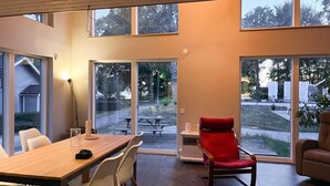 A modern interior with a dining area, a red chair, and large windows offering views of the outdoors. - 1 bedroom awesome home in Hörby (Hörby)