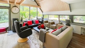 Una sala de estar moderna con techo alto, ventanas amplias y diferentes opciones de asientos.