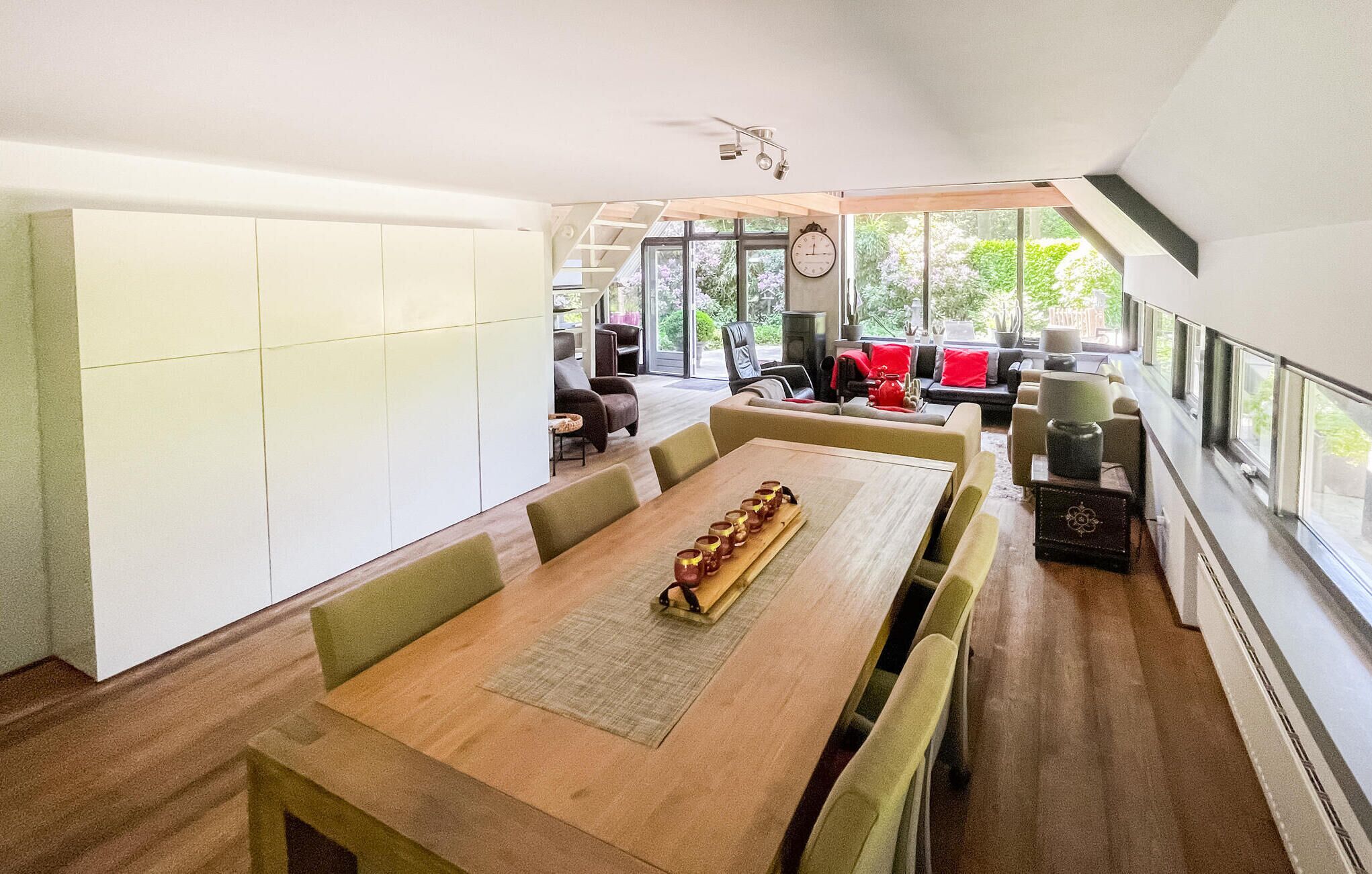 Un comedor amplio con una larga mesa de madera, múltiples sillas y una cocina moderna al fondo.