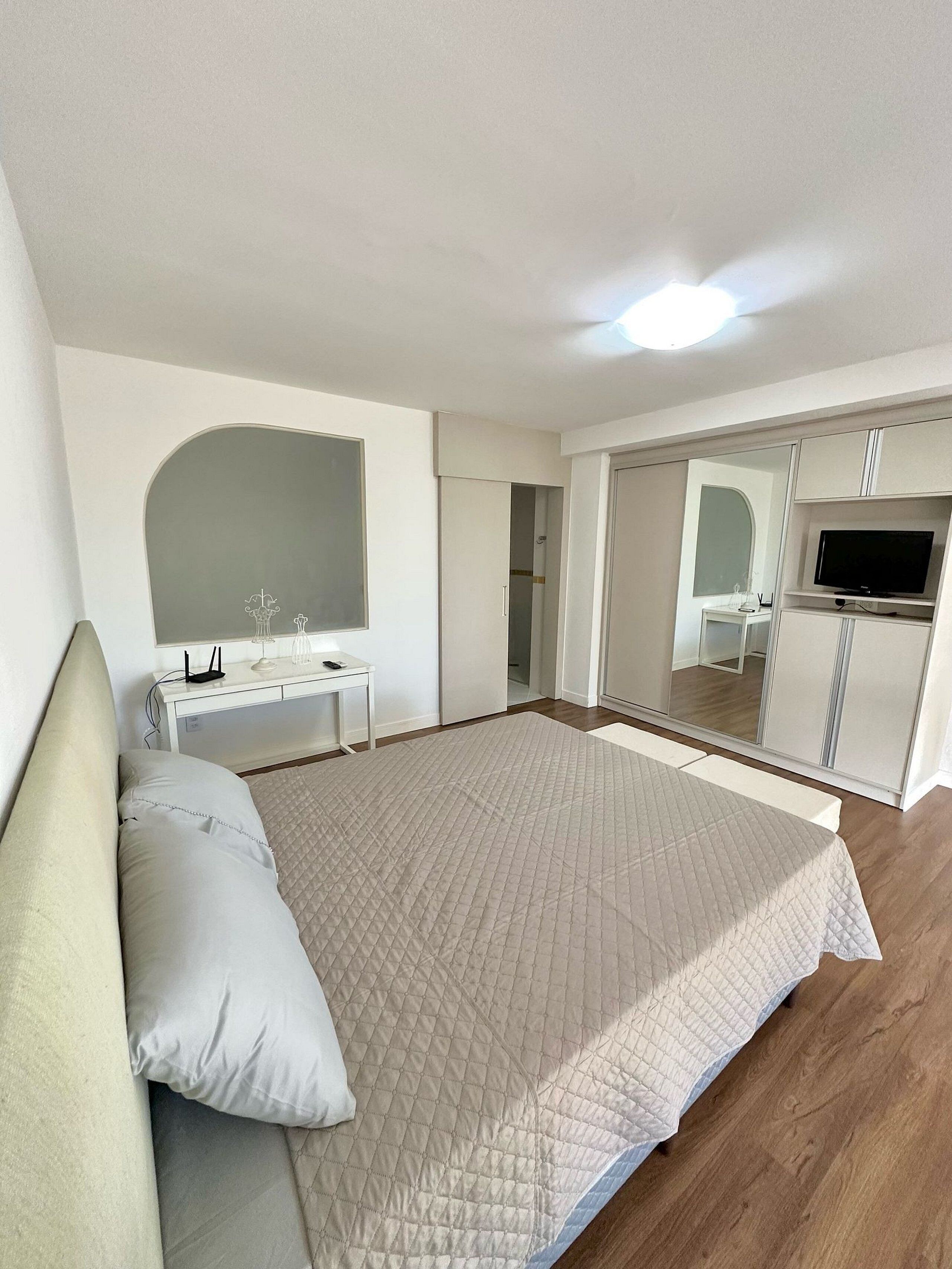 A bedroom with a bed, a desk, a TV, and a wardrobe.
