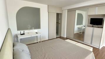 A bedroom with a bed, a desk, a TV, and a wardrobe.