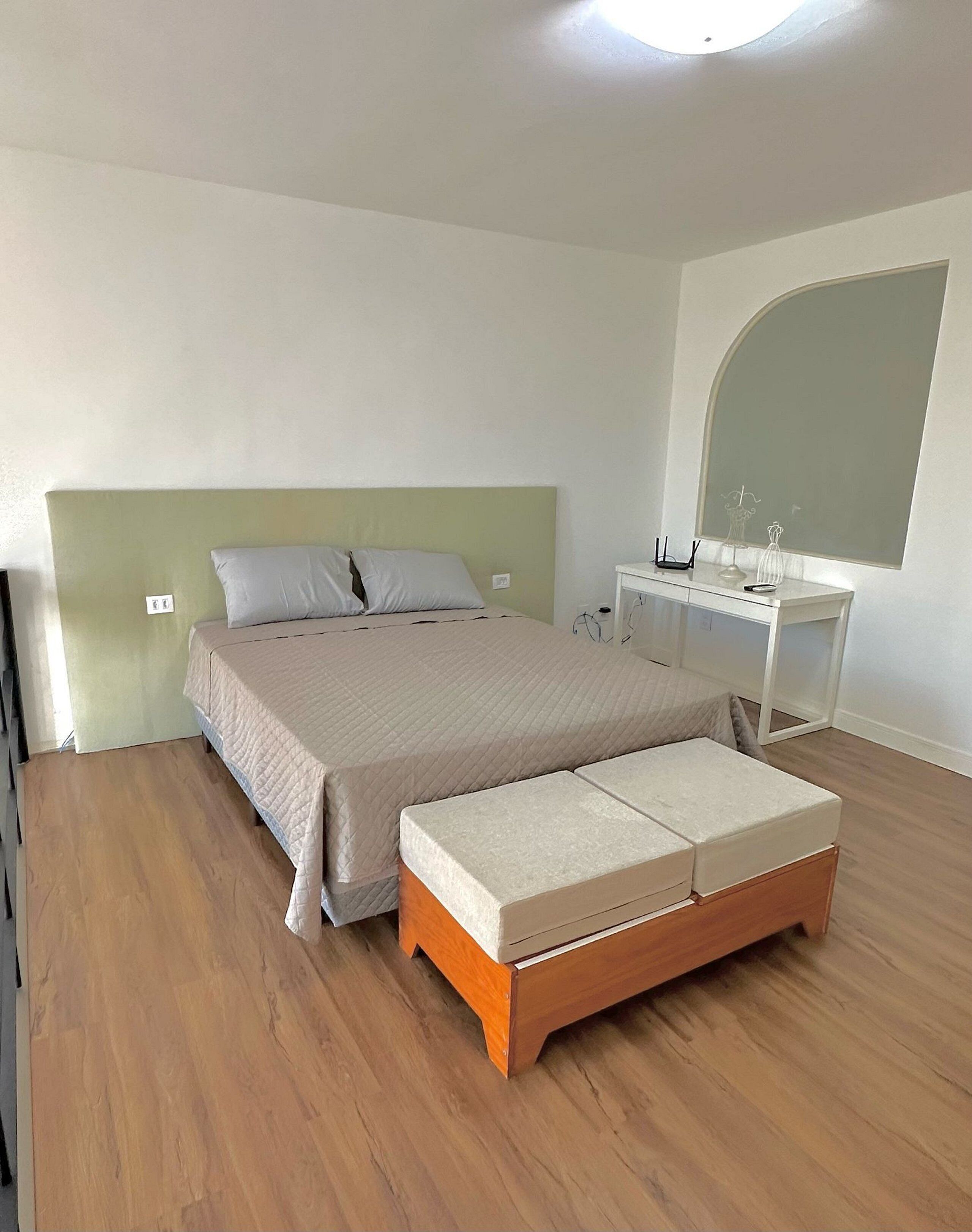 Une chambre à coucher avec un lit, une table de chevet et un miroir.