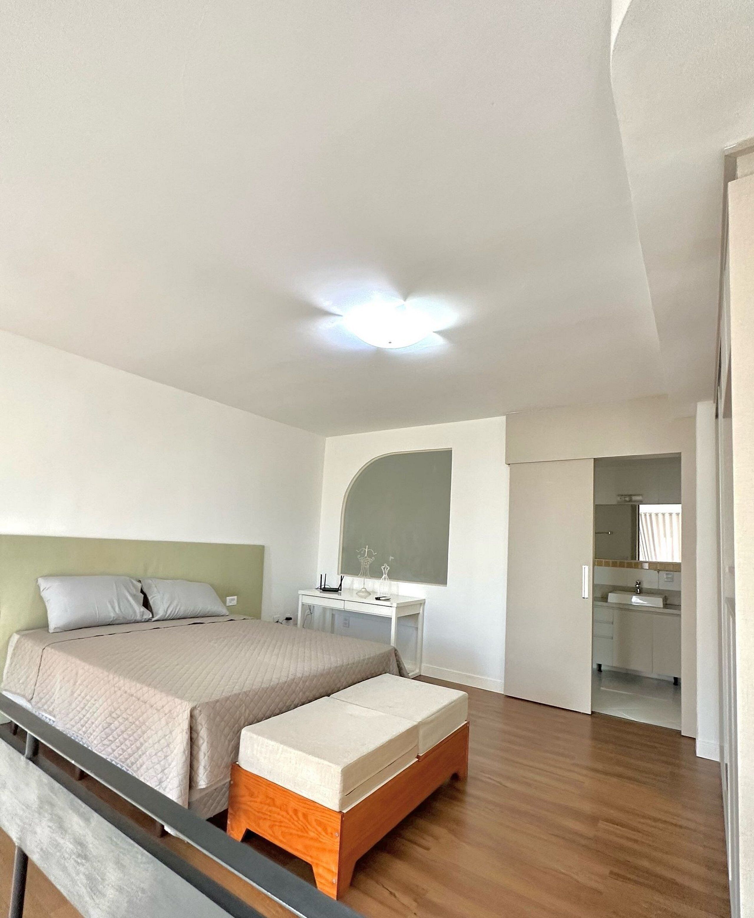 Ein Schlafzimmer mit Bett, Schreibtisch und angrenzendem Badezimmer.