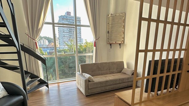 A modern living room with a staircase, a sofa, and a wooden partition. - Saint Sebastian 307 Duplex no Centro. (Jaragua do Sul)