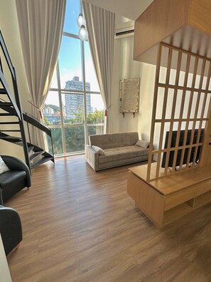 A modern living room with a staircase, a sofa, and a wooden partition. - Saint Sebastian 307 Duplex no Centro. (Jaragua do Sul)