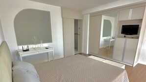 A bedroom with a bed, a dresser, a mirror, and a television. - Saint Sebastian 307 Duplex no Centro. (Jaragua do Sul)
