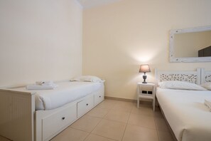 Une chambre avec deux lits, une table de chevet avec une lampe, un miroir et une petite armoire.