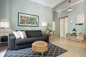 A modern living room with a grey sofa, round wooden coffee table, and a colorful abstract painting on the wall. - Olimpico Apartment Flaminio (Roma)