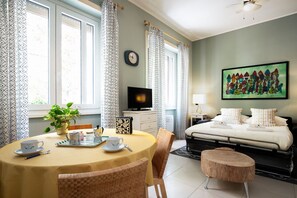 A bedroom with a bed, a TV, a painting, a bedside table, and a window with curtains. - Olimpico Apartment Flaminio (Roma)