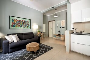 Una sala de estar moderna con un sofá, una mesita redonda y un cuadro abstracto de colores.