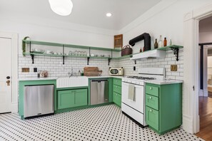 A kitchen with green cabinets, white appliances, and a patterned floor.