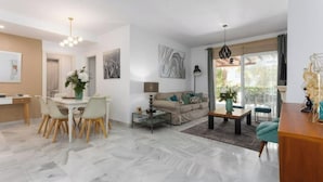 A modern living room with a dining area, a sofa set, and a coffee table. - Magnífico Apartamento guadalmina baja  (Marbella)