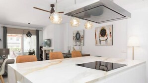 A modern kitchen with a large island, pendant lighting, and artwork on the walls. - Magnífico Apartamento guadalmina baja  (Marbella)