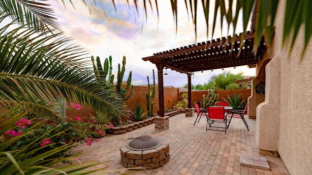 An outdoor patio with a pergola, brick flooring, and a stone fire pit.