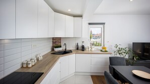 Una cocina moderna con armarios blancos, encimera de madera y horno empotrado.