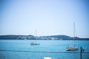 A calm lake with two sailboats anchored near the shore.