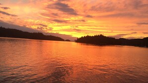 Ein ruhiger See im Abendrot mit bewaldeter Uferlinie.
