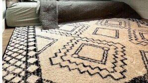 A loft bedroom with a skylight, a patterned rug, and a bed with pillows. - Urban Tiny Home Getaway
 (Caldwell)