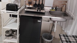 Ett litet, praktiskt pentry med kaffebryggare, brödrost, spis och en liten papperskorg.
