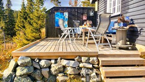 Une terrasse en bois avec un mur en pierre, une table avec des chaises et un tableau accroché au mur.