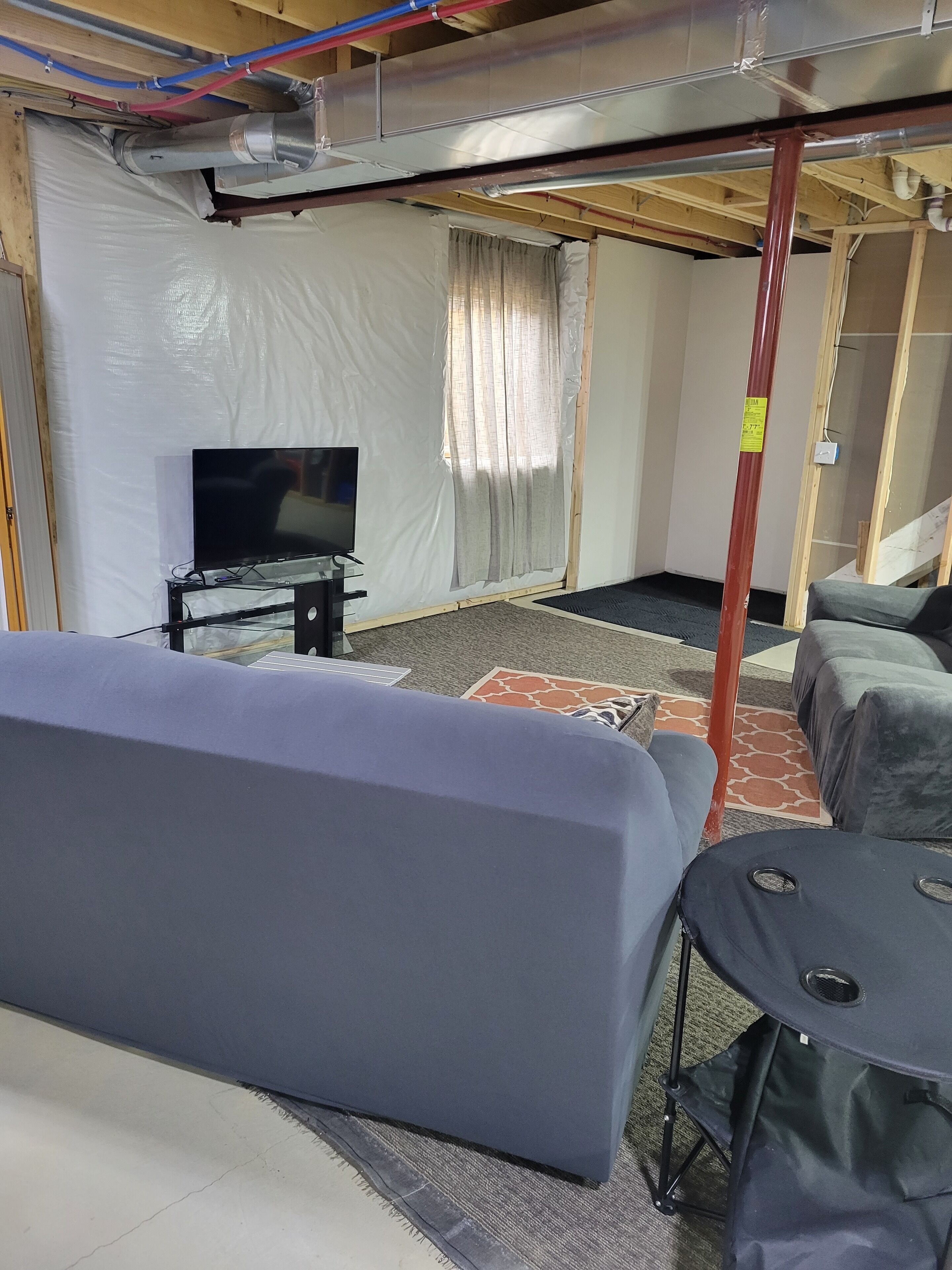 Ett rum med en soffa, ett litet bord, en tv och ett fönster med gardiner.