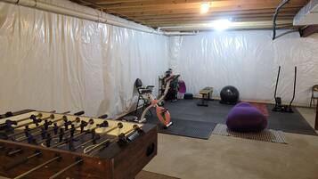 Una cantina con un tavolo da calcio, attrezzature per l'esercizio fisico e una zona coperta con pareti in plastica.