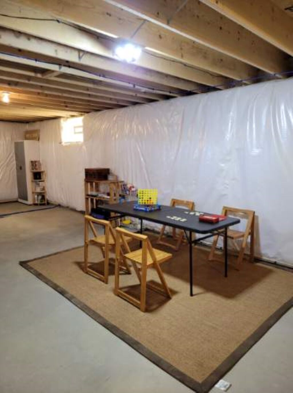 Une pièce avec une table et des chaises, une bibliothèque et un rideau blanc.