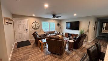 A spacious living room with a fireplace, a television, and a ceiling fan.