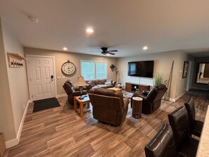 A spacious living room with a fireplace, a television, and a ceiling fan. - New 4BR/2BA Lake of the Woods Walleye Camp! (Baudette)