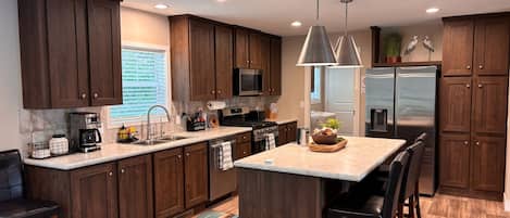 A modern kitchen with dark wood cabinets, stainless steel appliances, and a central island with seating.