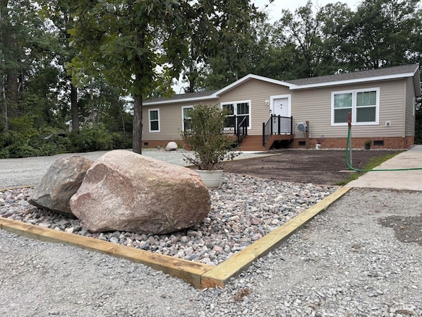 A single-story house with a front porch, a large rock garden, and a potted plant.
