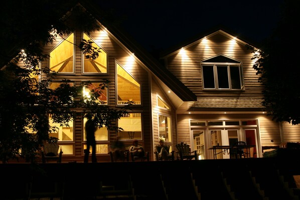 Stunning two-story house with a gabled roof and inviting front porch featuring large windows and a cozy seating area.