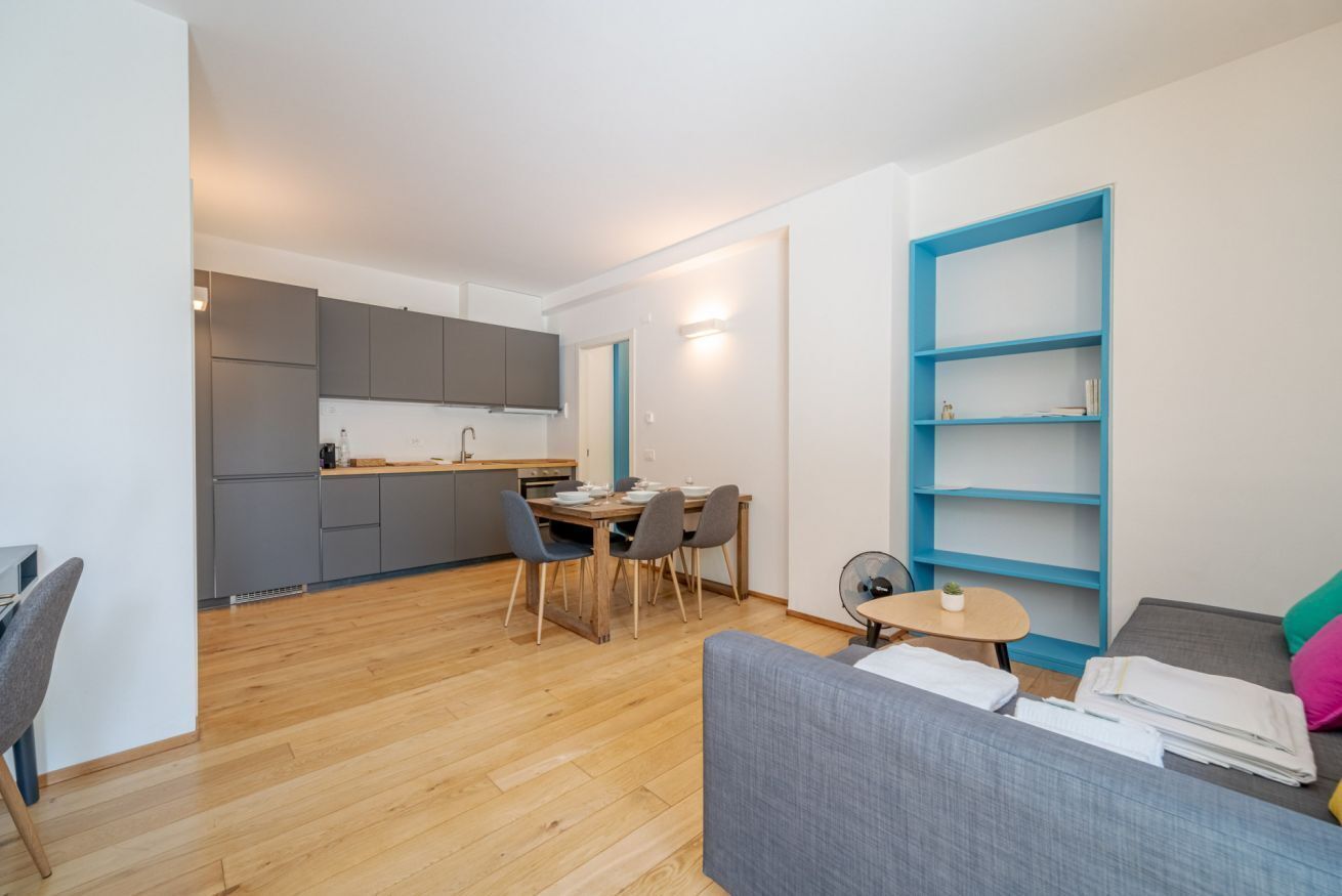 A modern apartment with a dining area, kitchenette, and a living space with a sofa and a small table.